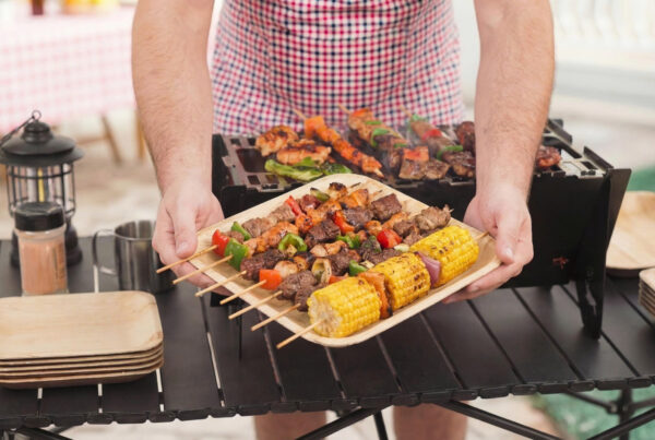 Stack of heavy duty palm leaf plates set with colorful BBQ food, showing natural texture and sturdy edges